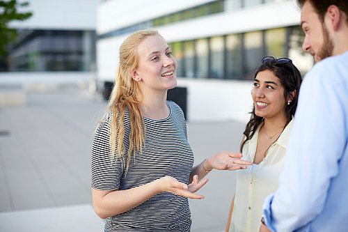 Drei diskutierende Studierende vor der Uni